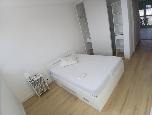 a white bed in a room with a wooden floor at Eves Rooms in Saint-Michel-sur-Orge