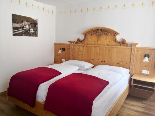 a bedroom with a large bed with a wooden headboard at Landhotel Postgut - Tradition seit 1549 in Tweng
