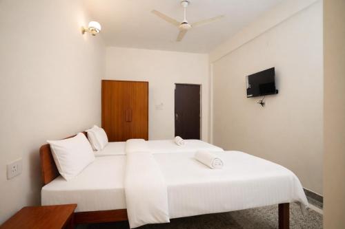 a bedroom with two beds and a tv on the wall at Gangabagh by Divine Trails - Hotel Near Har Ki Pauri, Haridwar in Haridwār