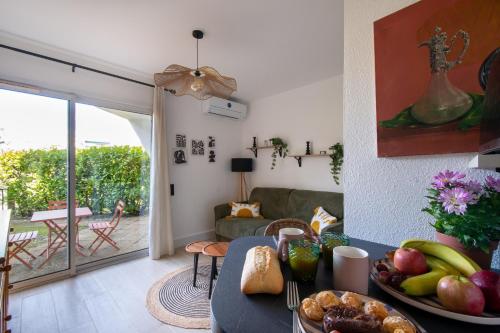 a living room with a table with a bowl of fruit at Jardin du Golf wifi Clim in La Grande Motte