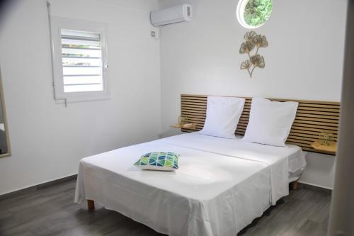 a white bedroom with a bed with a window at La kaz a sonel, gîte au vert in Morne-à-lʼEau