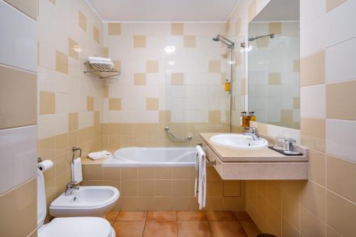 a bathroom with a tub and a toilet and a sink at AP Victoria Sports & Beach in Albufeira