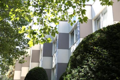 a white building with trees in front of it at Central Hotel Eschborn in Eschborn