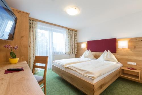 a bedroom with a bed and a desk and a television at Sonnhof in Ramsau am Dachstein