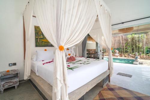 a bedroom with a canopy bed and a swimming pool at Jellyfish2 2BR for Groups, 5 Min to Thomas Beach in Uluwatu