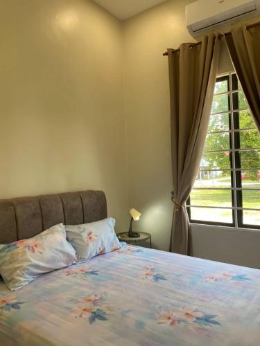 a bedroom with a bed with a window at Homestay Lanai Kemboja Sungai Buloh in Shah Alam