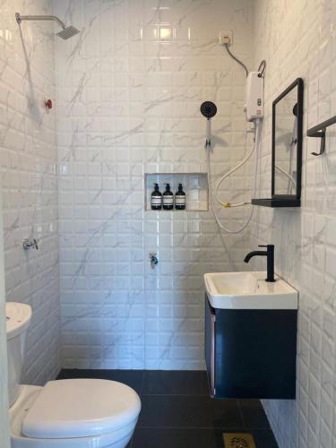 a white bathroom with a toilet and a sink at Homestay Lanai Kemboja Sungai Buloh in Shah Alam