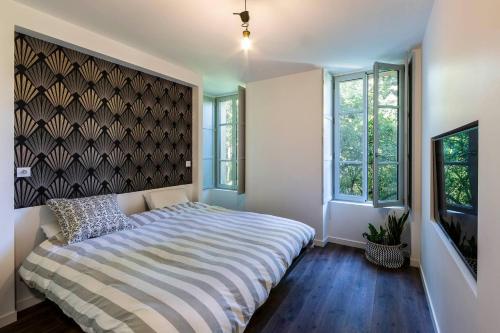 a bedroom with a bed and two windows at Moulin in Vitré
