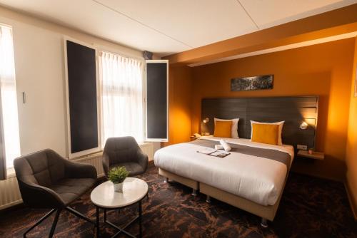 a hotel room with a bed and two chairs at Hotel The Happy Traveler in Groningen