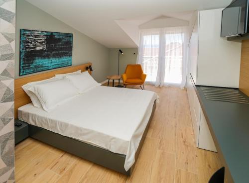 a bedroom with a large white bed and a chair at Seaview Villa Rajmond in Podstrana
