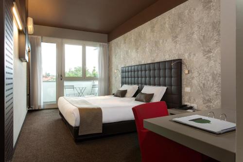 a bedroom with a large bed and a desk with a red chair at Best Western Hotel Continental in Udine
