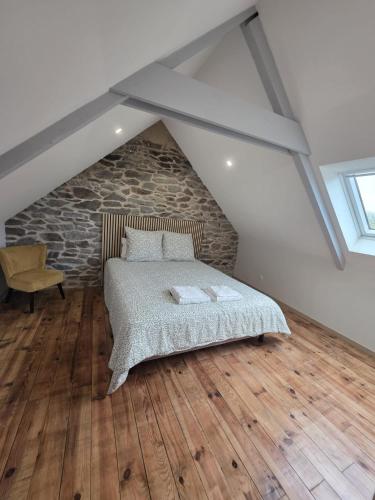 a attic bedroom with a bed and a stone wall at L'hyère in Carhaix-Plouguer