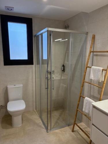 a bathroom with a glass shower and a toilet at Hostal Mallorquines in Riudarenes