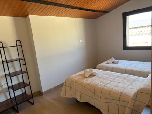 a room with two beds and a ladder and a window at Hostal Mallorquines in Riudarenes