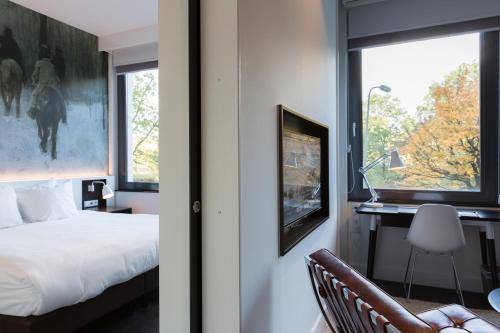 a bedroom with a bed and a desk and a window at B-aparthotel Kennedy in The Hague