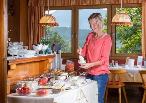 a woman standing in front of a table with food at Sonnhof in Ramsau am Dachstein