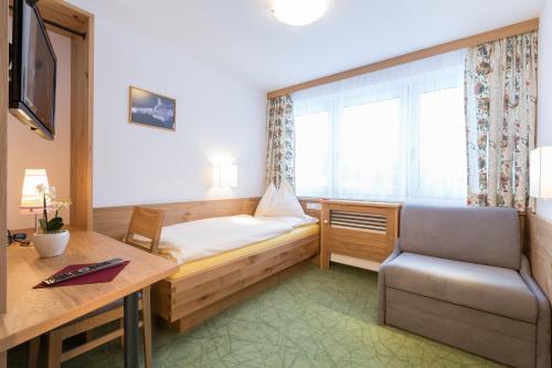 a room with a bed and a chair and a desk at Sonnhof in Ramsau am Dachstein