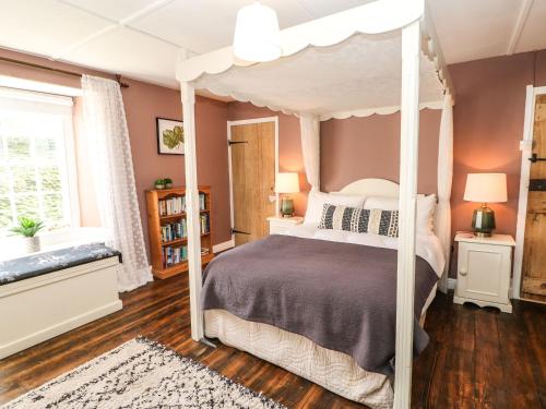a bedroom with a canopy bed and a wooden floor at Englewood Cottage in Hexham