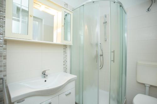 a white bathroom with a sink and a shower at Apartmani Zlata in Rabac