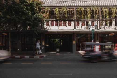 a person riding a skateboard down a street in front of a building at Baan Tuk Din Hotel in Bangkok
