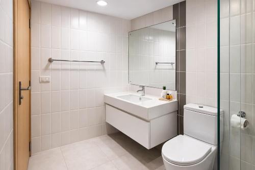 a white bathroom with a toilet and a sink at NexStay Bangkok Appartment in Bangkok