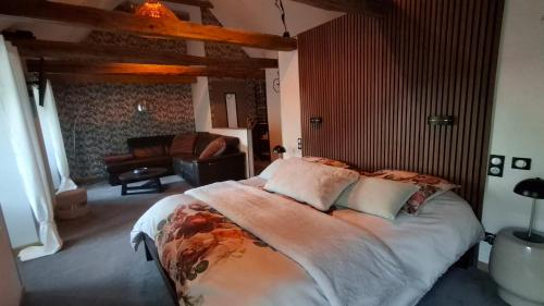 a bedroom with a large bed and a living room at Le Mas ROLLAND -Chambres de charme -SPA sauna & jacuzzi - Label Qualité Tourisme Occitanie - Millau - Gorges du Tarn in Compeyre