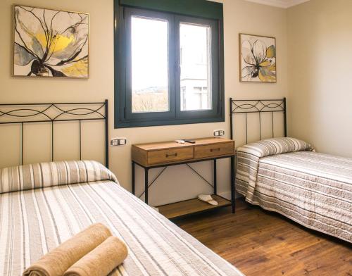 two beds in a room with a window at Pensión Casa Rego Sarria in Sarria