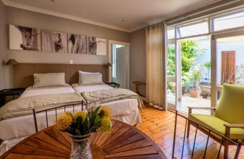 a bedroom with two beds and a table with flowers on it at B's Place in Port Elizabeth