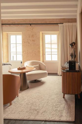 a living room with a couch and a table and two windows at Château Fonroque - Camomille in Saint-Émilion