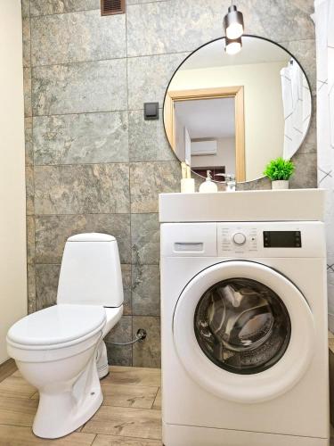 a bathroom with a washing machine and a mirror at Dunes Trail 4 in Melnragė