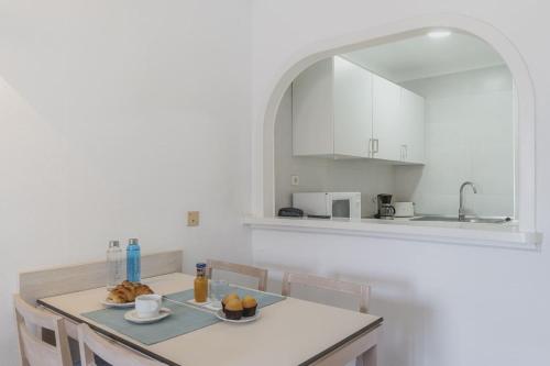 a white kitchen with a table and chairs and a sink at Apartamentos Casa Vida in Santa Ponsa