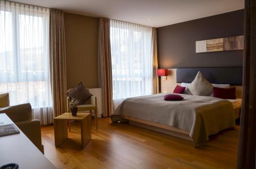 ein Schlafzimmer mit Bett, Stuhl und Fenstern in der Unterkunft Sternen Hotel Wolfurt in Bregenz