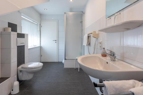 a white bathroom with a sink and a toilet at Rixbecker Alpen - Hotel Koch in Lippstadt