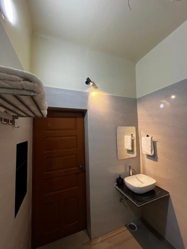 a bathroom with a sink and a wooden door at Prangan - The Villa in Chākdaha