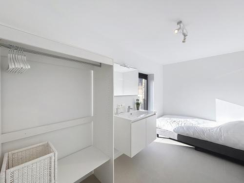 a white bathroom with a sink and a bed at Villa Pomone - Sint-Idesbald in Koksijde
