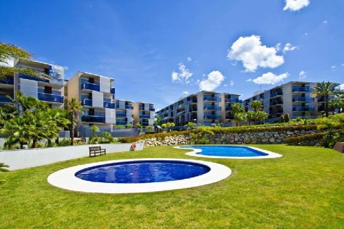 a large pool in the middle of a lawn with buildings at UHC Paradise Village Family Complex in Salou