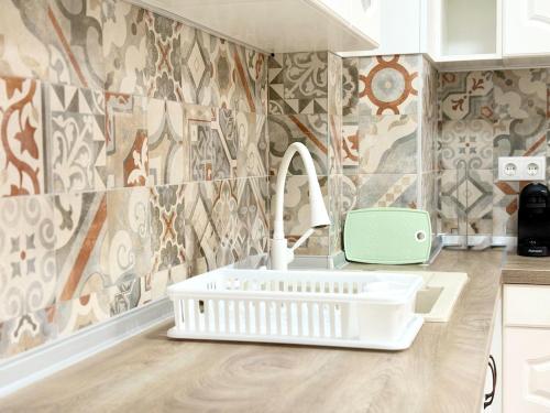 a kitchen with a white sink and a tile wall at Modern Nest Varna - free parking in Varna City
