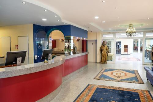 a lobby with a statue in the middle of a building at Hotel Königshof am Funkturm in Hannover