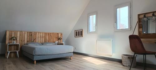 a bedroom with a bed and a chair and two windows at Logement 1 - proche Le Mans in Aigné