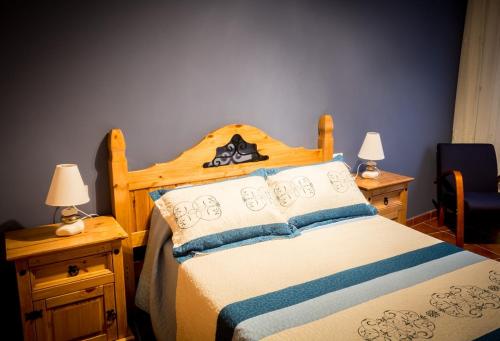 フェルモセリェにあるCasa Rural el Mesonのベッドルーム1室(木製ベッド1台、ナイトスタンド2台、ランプ2つ付)