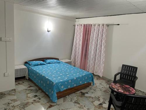 a small bedroom with a bed and a chair at Bagaicha Farms in Tādong