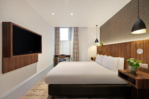 a hotel room with a bed and a flat screen tv at 91 Aparthotel Jesmond Road in Newcastle upon Tyne