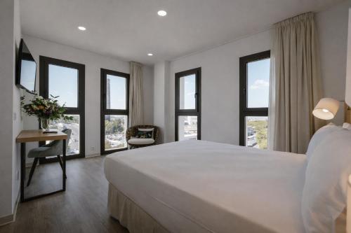 a bedroom with a large white bed and windows at Petit Palace Vargas in Seville