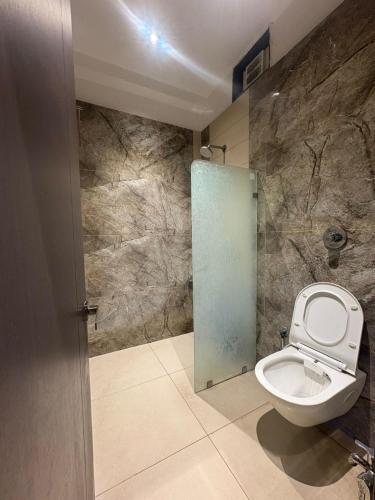 a bathroom with a toilet and a glass door at Hotel Govind Regency in Dhule