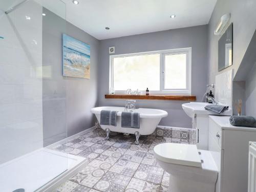 a bathroom with a tub and a toilet and a sink at Millers Loft in Llanrwst