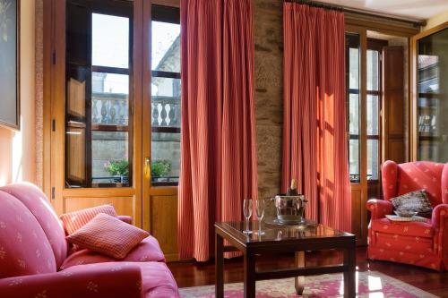a living room with red chairs and a table at Hotel Rua Villar in Santiago de Compostela