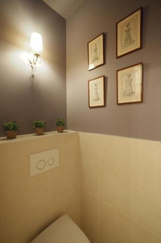 une salle de bains avec toilettes et trois photos sur le mur. dans l'établissement Louvre Opera Design ChicSuites, à Paris