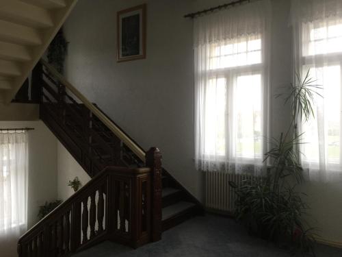 a staircase in a living room with windows and a stair case at Pension Villa Else in Heidenau