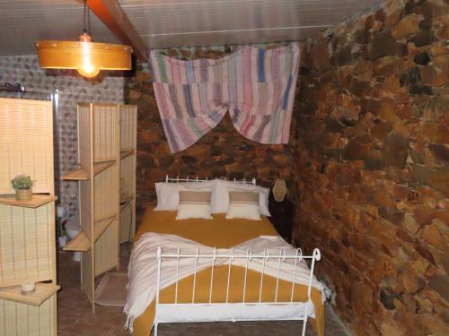 a bedroom with a bed and a stone wall at Monte Vilão in Soudes