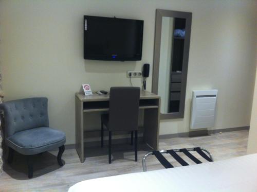 a room with a desk with a television and a chair at Hotel de la Couronne in Aix-les-Bains